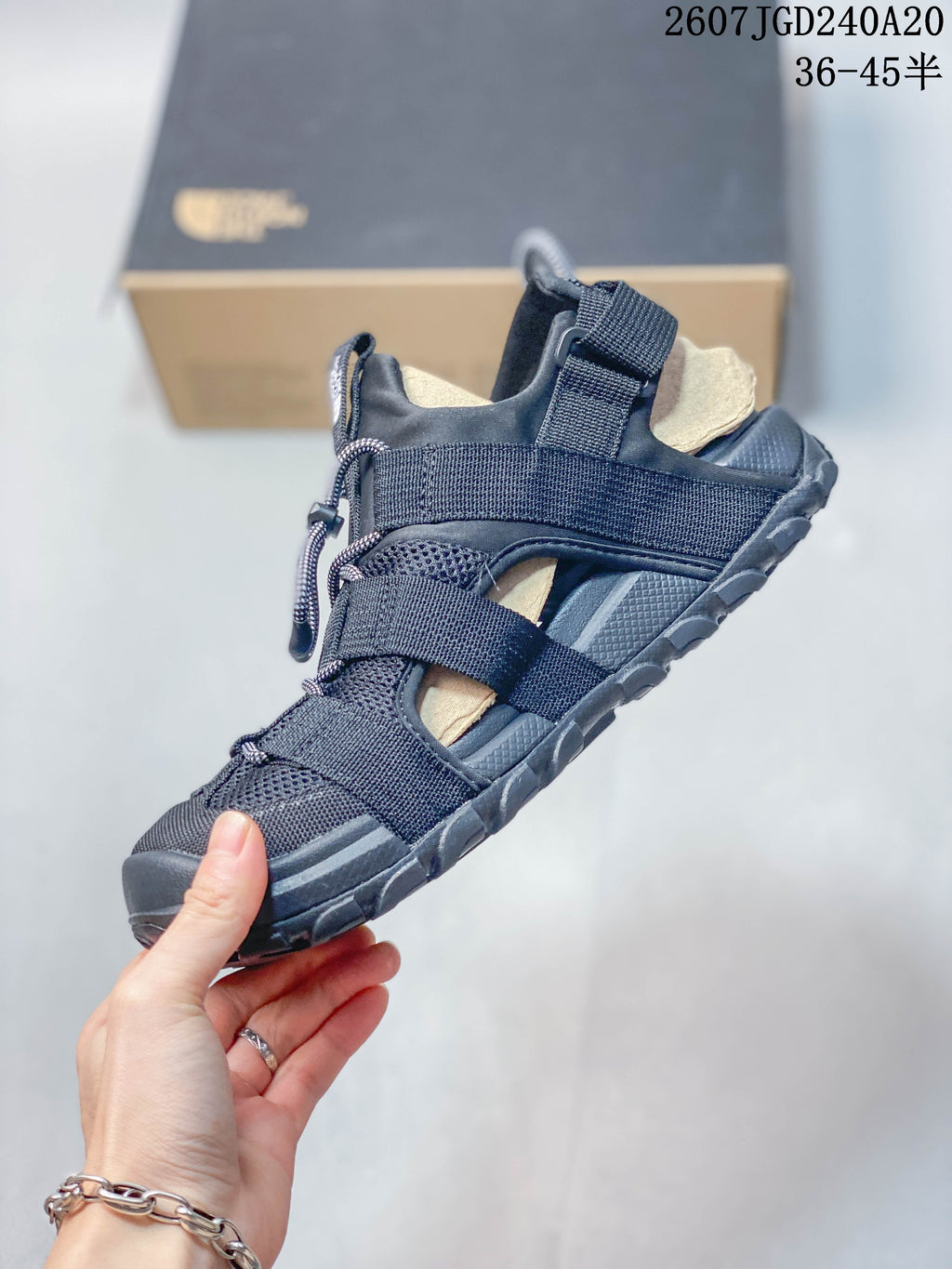 Side view of the black sandal showing layered adjustable straps, open side panels, mesh-like sections, and the rugged sole.