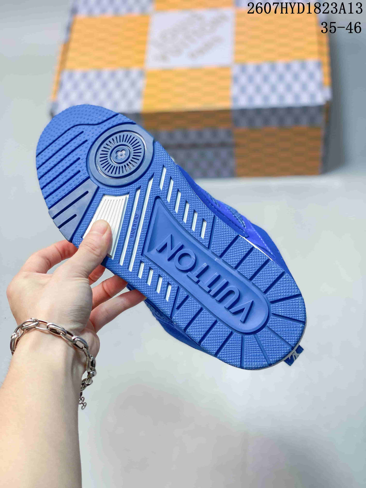 Blue sneaker outsole shown from below, featuring a circular pivot detail, textured tread, and raised branding.