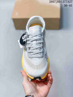 Top view of the white lace-up sneaker showing the tongue, laces, perforated upper panels, and yellow side accents.
