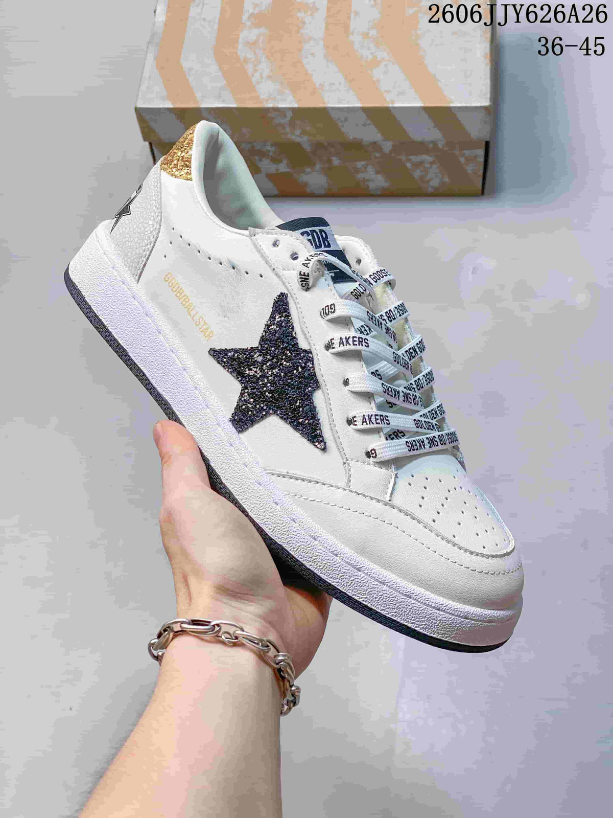Angled side view of the white sneaker showing the dark glitter star, gold side text and contrasting outsole.