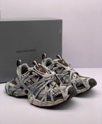 Three-quarter front view of the Balenciaga 3XL sneakers with layered gray laces and contrasting toe panels.