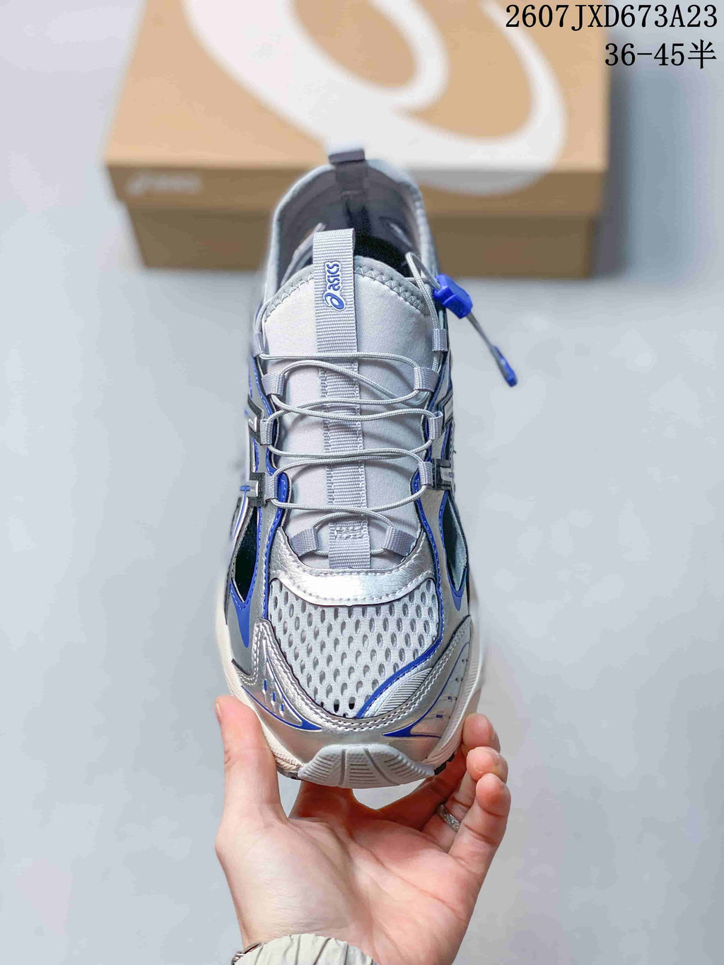 Top view of the sneaker showing the silver mesh toe area, gray laces, tongue branding, and blue trim.