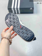 Underside view of a shoe showing the dark geometric traction outsole and adidas branding.