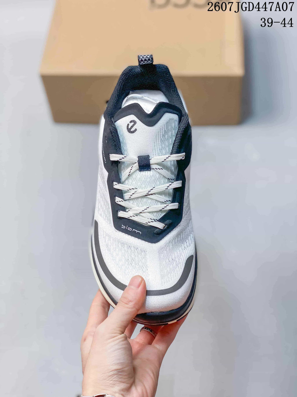 Top view of the sneaker showing white laces, a navy lace panel, gray toe detailing, and the ECCO logo mark.