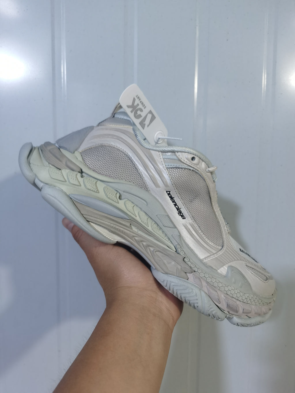 Close angled view of the off-white Balenciaga sneaker showing side branding, mesh panels, and the multi-section sole.