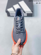 Top view of an Adidas Supernova Rise sneaker showing the lace-up construction, dark gray knit-look upper, and orange side sole; image text shows size range 40–45.