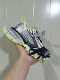 Close-up view of a Nike sneaker in white, black, gray, and fluorescent yellow with layered panels and black laces.