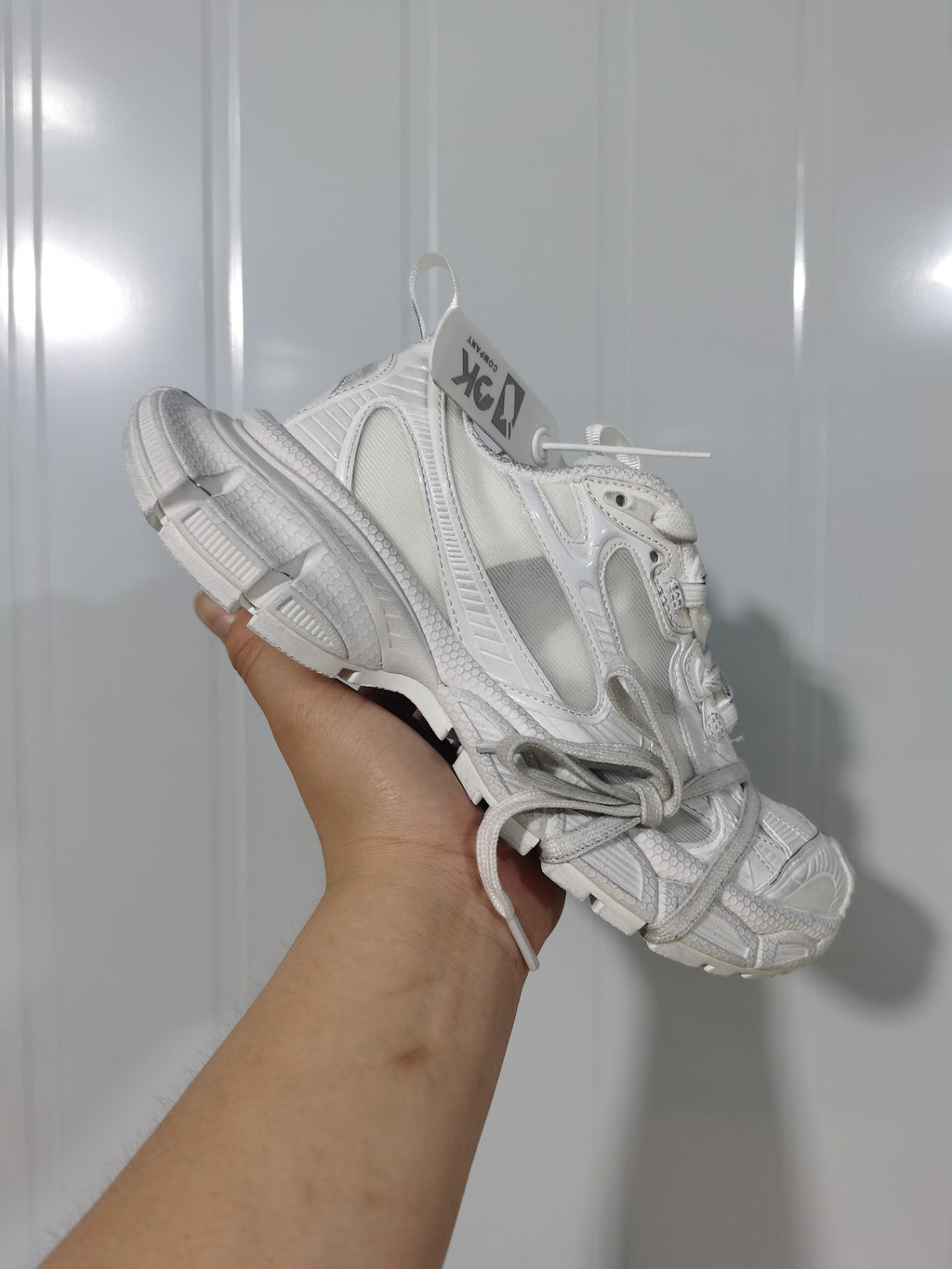 Angled top view of a snow white sneaker with lace fastening, layered upper panels, and an Off-White-branded hangtag.