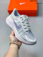 Angled close-up of a light gray Nike Air Zoom Winflo 8 shoe with purple and teal side accents, mesh-style upper, and textured midsole.