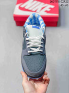 Top view of the sneaker showing the perforated grey toe panel, white laces, and blue patterned lining.