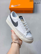 Close-up of a white Nike Blazer Low Premium sneaker with a dark Swoosh, black tongue label, white laces and an off-white sole.