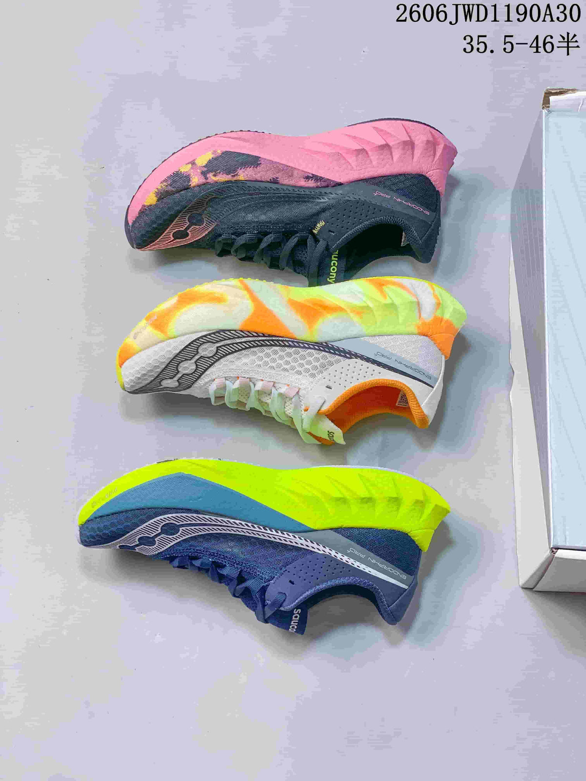 Three Saucony running shoes shown in charcoal and pink, white and orange, and navy and lime colorways