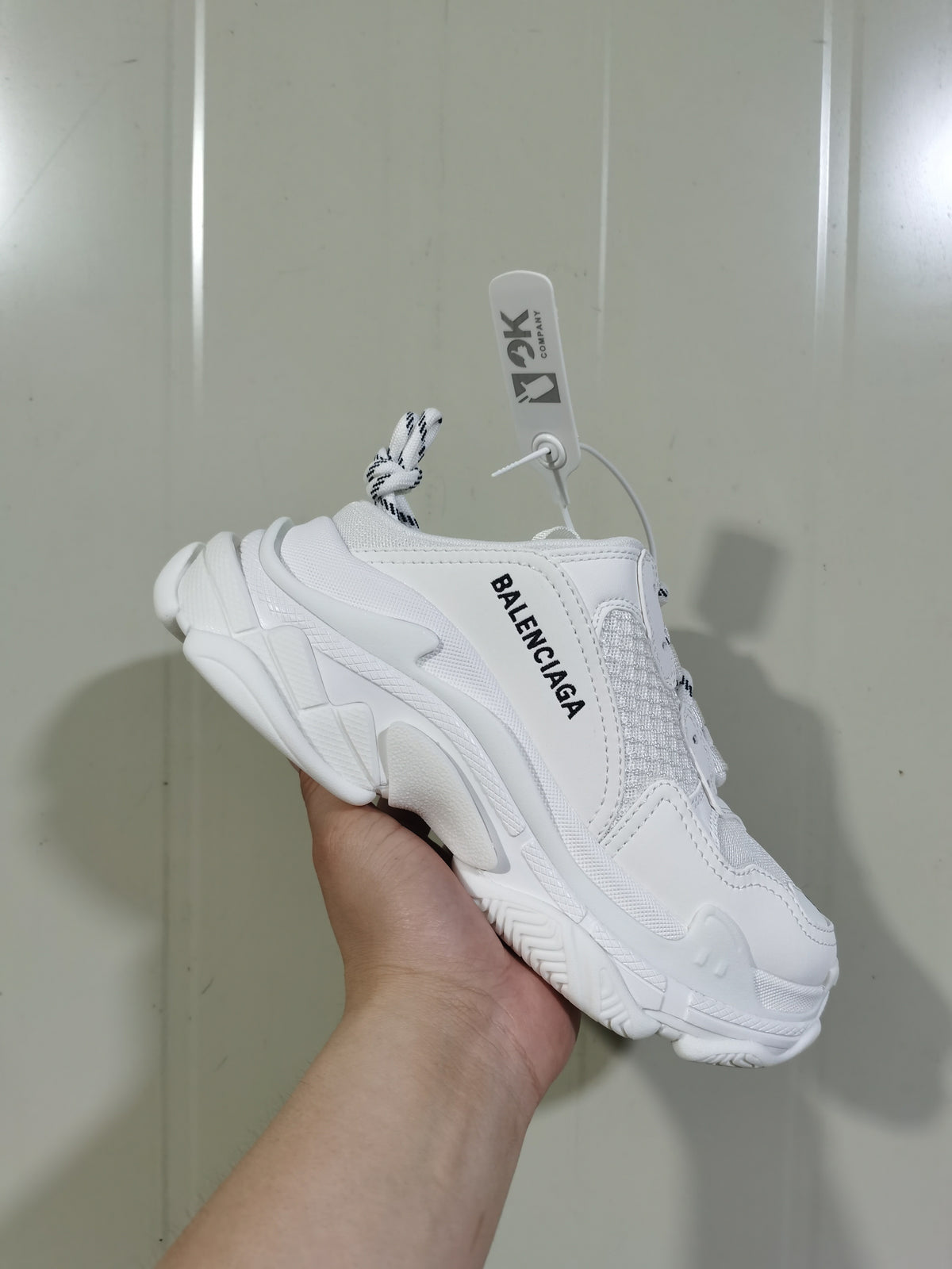 Angled view of the white Balenciaga sneaker showing the side branding, layered upper, mesh panels, and chunky textured outsole.
