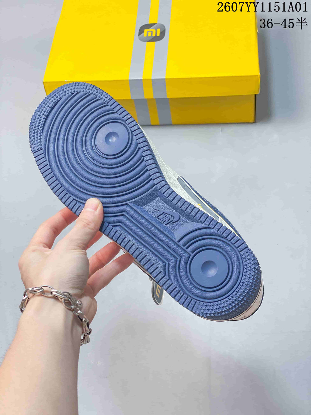 Blue outsole of the Nike Air Force 1 ’07 Low sneaker beside a yellow box.