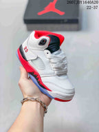White kids' mid-top sneaker with red outsole accents, red collar lining, and a dark tongue panel.