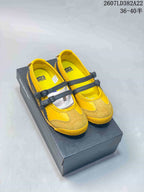 Yellow and black low-top shoes with twin buckle straps displayed on a shoe box.