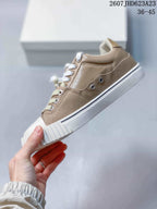 Side profile showing taupe upper panels, white laces, metal eyelets, and a thick white sole.