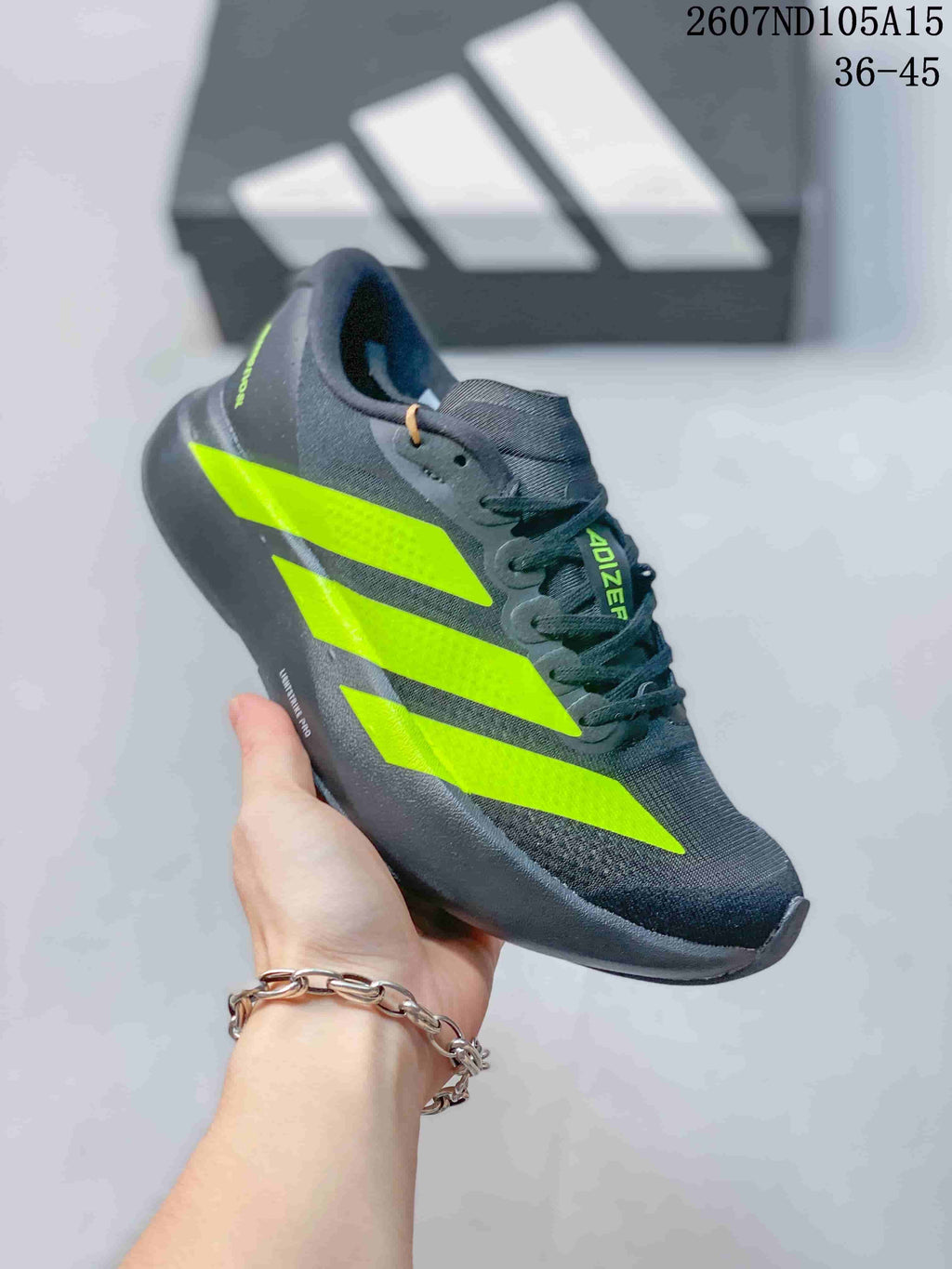 Side view of a dark gray Adidas Adizero sneaker with bright green stripes.