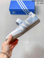 Side view showing the pale blue upper, white stripes, Mary Jane strap, and gum-colored outsole.