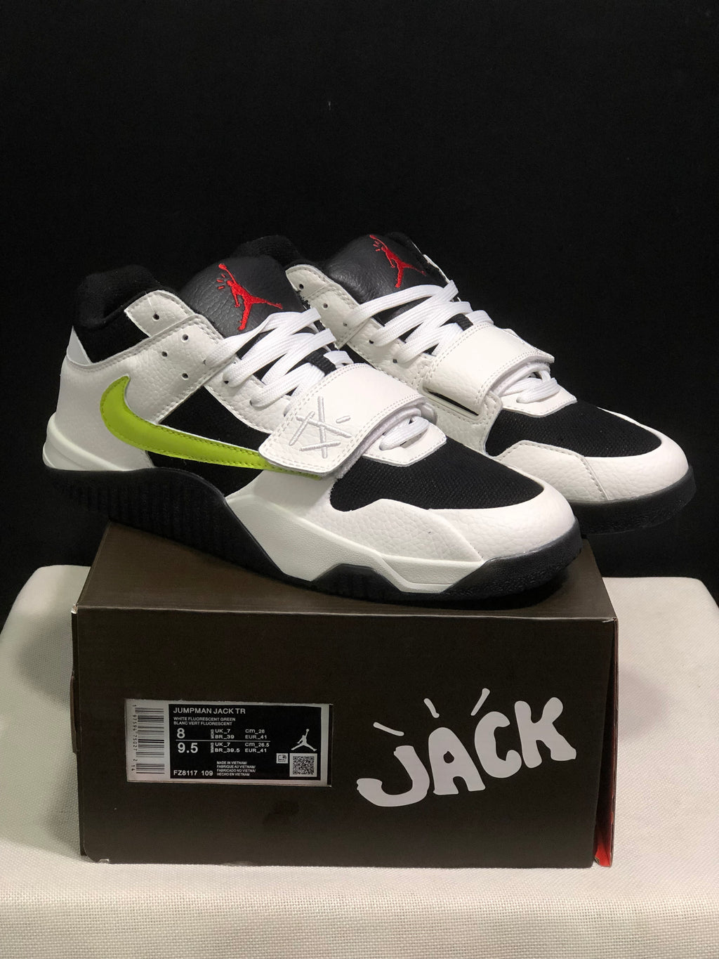 Pair of white, black, and fluorescent green Jumpman Jack TR sneakers displayed on the branded shoe box.