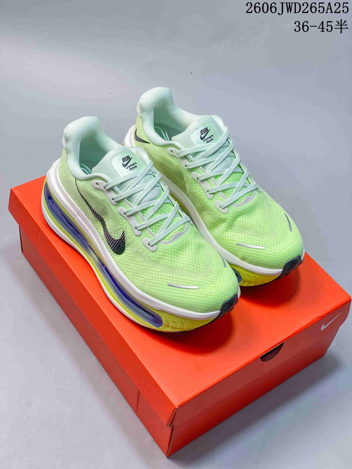 Pair of lime-green Nike Vomero Premium running shoes displayed on an orange shoe box.