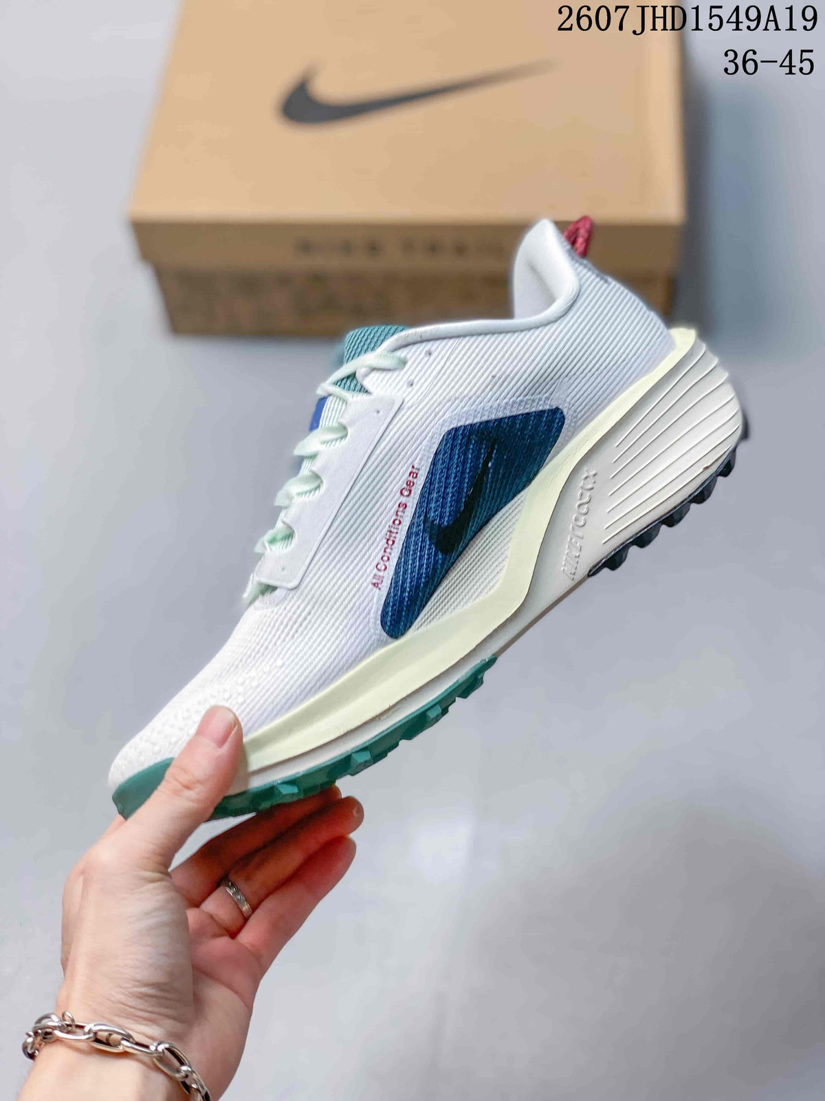 Side profile showing the white textured upper, blue layered side detail, sculpted midsole, and outsole.
