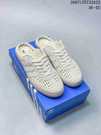 Off-white adidas Samba OG mule-style sneakers displayed on a blue shoebox, showing woven toe and side panels.