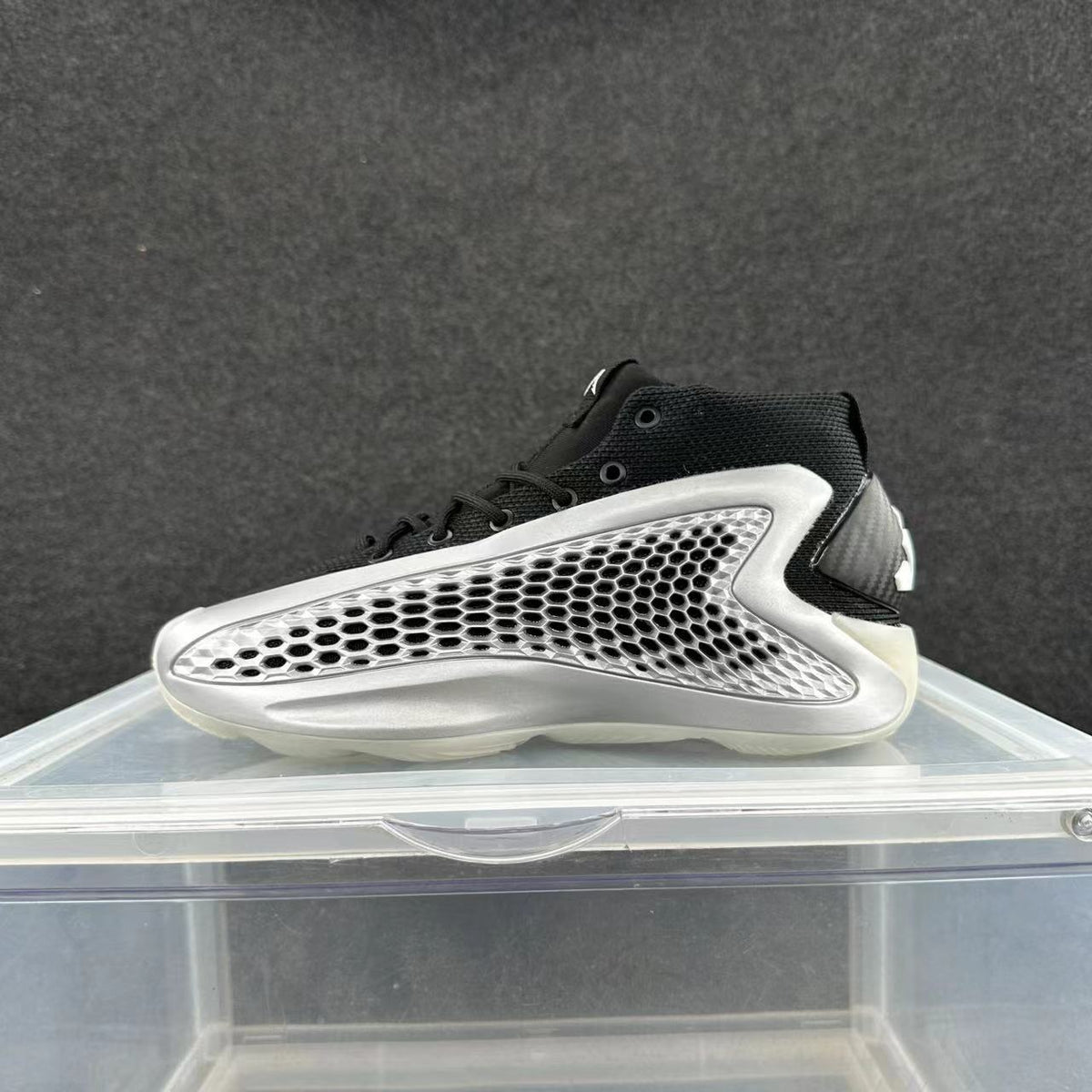 Black high-top sneaker with a sculpted silver mesh-pattern side panel.