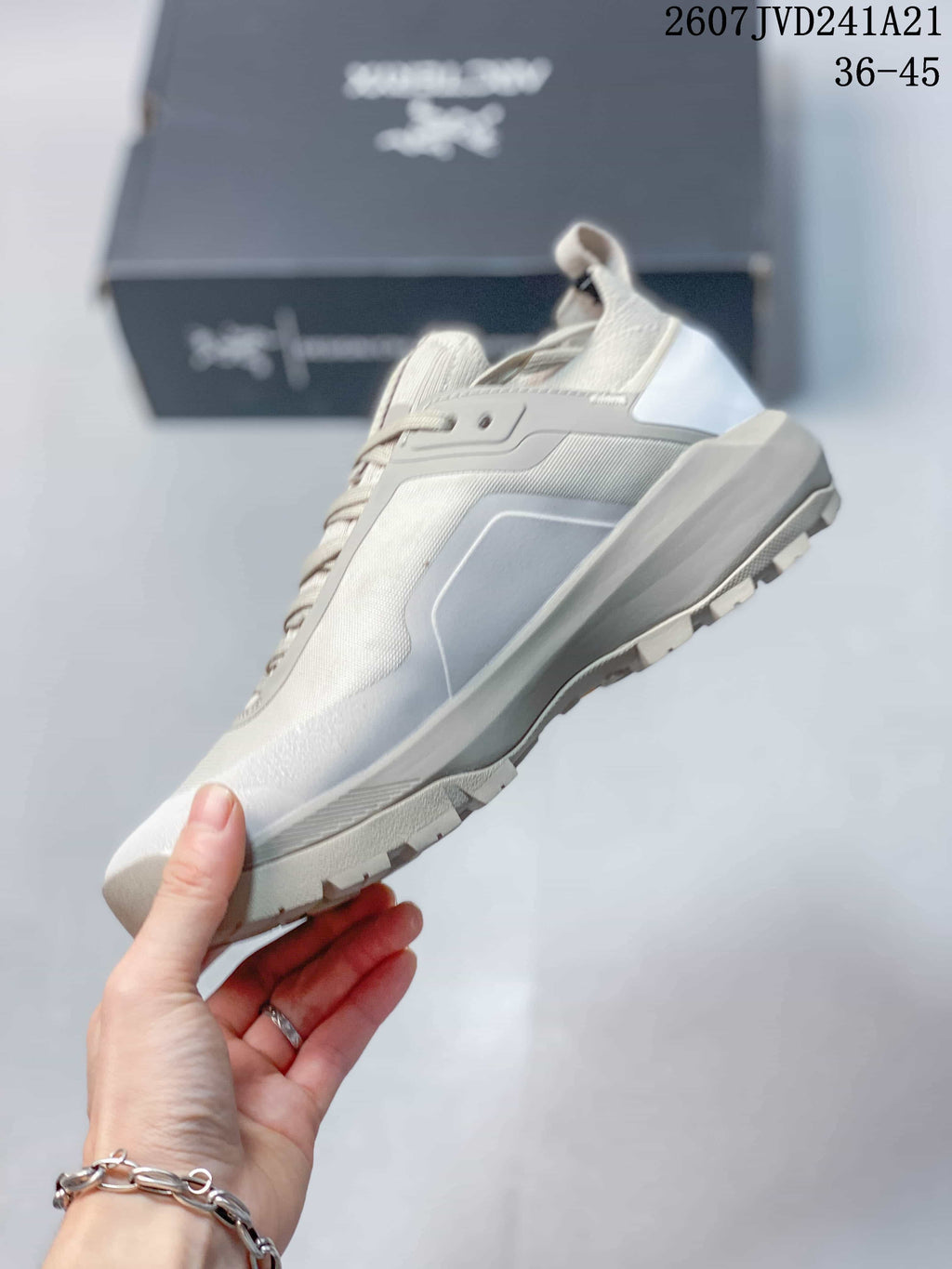 Side view highlighting the light gray upper, layered panels, midsole, and outsole lugs.
