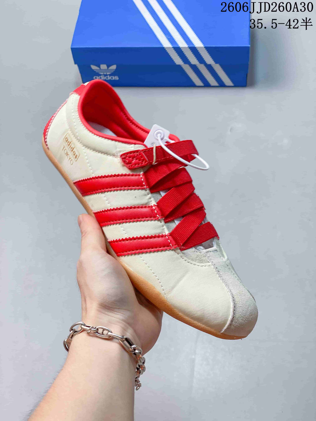 Side view of a cream and red Tokyo MJ sneaker, showing the side stripes and strap-and-lace closure.