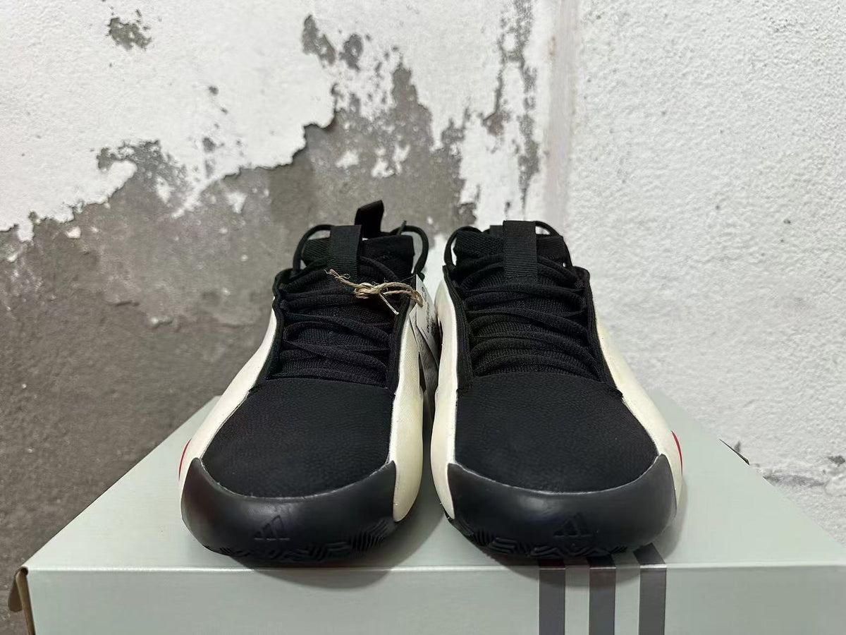 Front view of black lace-up sneakers with white side edges and dark toe guards