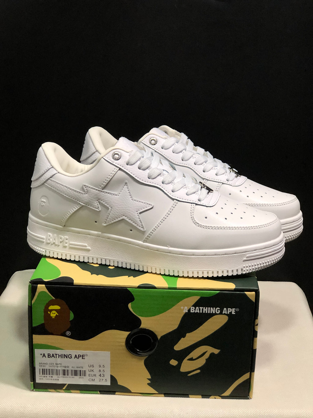 White BAPE Bape Sta sneakers displayed on a camouflage BAPE shoe box; the box label shows US 9.5, UK 8.5, EU 43, and CM 27.5.