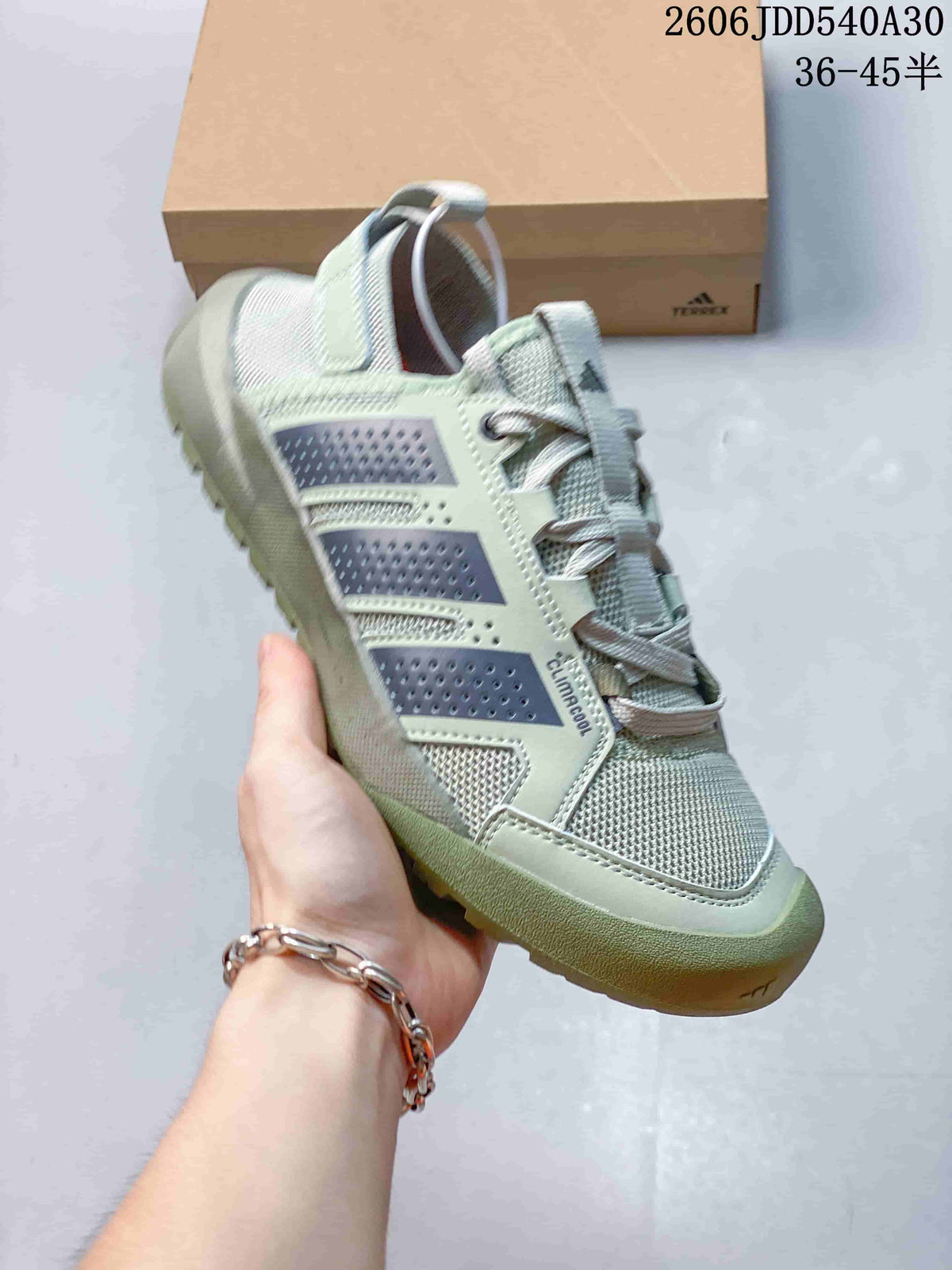 Angled side view of the pale sage-green sneaker