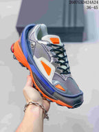 Close-up of a silver-gray, navy, orange, and blue OZWEEGO sneaker with black laces and a contrasting outsole.