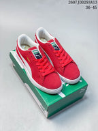 Pair of red and white PUMA low-top sneakers displayed on a green PUMA shoebox.