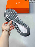 Underside view of a gray Nike sneaker showing the patterned rubber outsole and orange Nike shoebox.