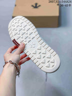 White sneaker outsole showing a geometric traction pattern, embossed central branding and a burgundy outsole insert.