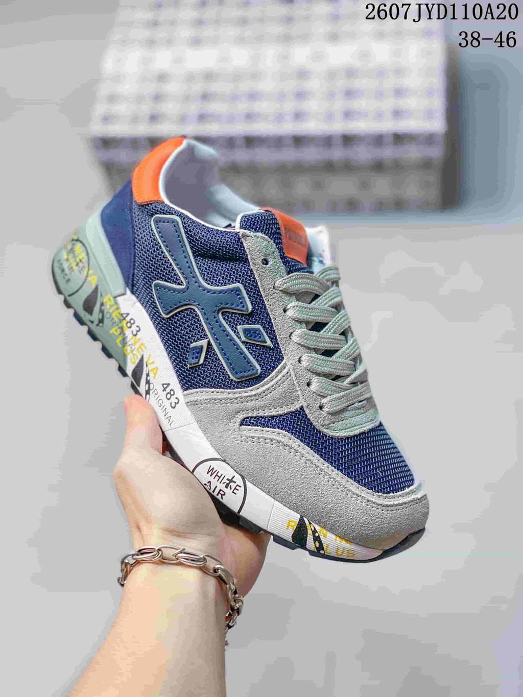 Blue Premiata sneaker with gray overlays, orange heel detail, and a printed midsole.
