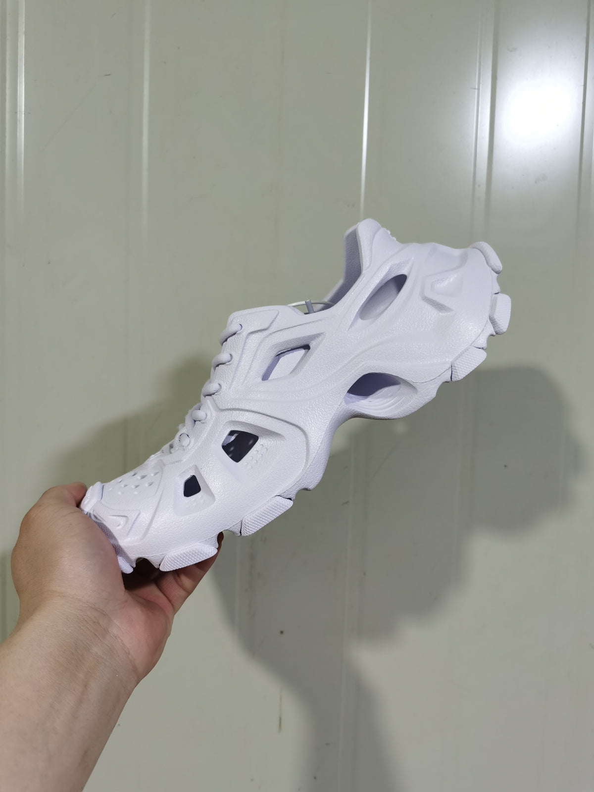 Top and side view of the white sneaker, showing its lace-up upper, open-panel details, and sculpted sole.