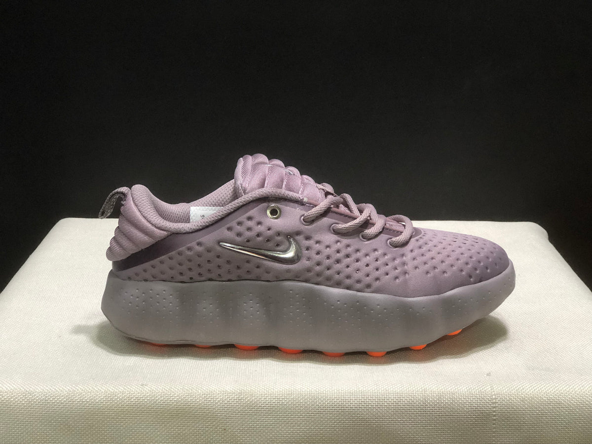 Side view of a single purple Nike Mind 002 sneaker with orange outsole details.