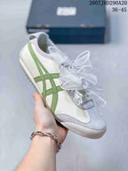Angled side view of the white and green low-top sneaker with light gray toe detailing and ribbon laces.