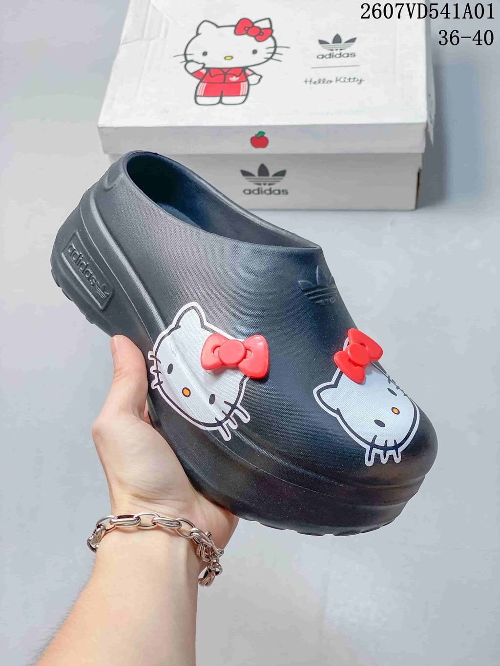Angled view of a charcoal clog mule with Hello Kitty graphics and red bows.