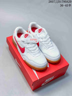White and red Nike Terra Manta Suede sneakers displayed on a red shoebox, showing the gum-colored outsole.