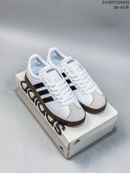Pair of white Adidas Neo VL Court 2.0 sneakers with black side stripes and gum-colored soles displayed on an Adidas shoebox.