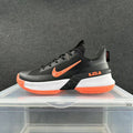 Side view of a black Nike LeBron basketball shoe with orange accents and a white midsole