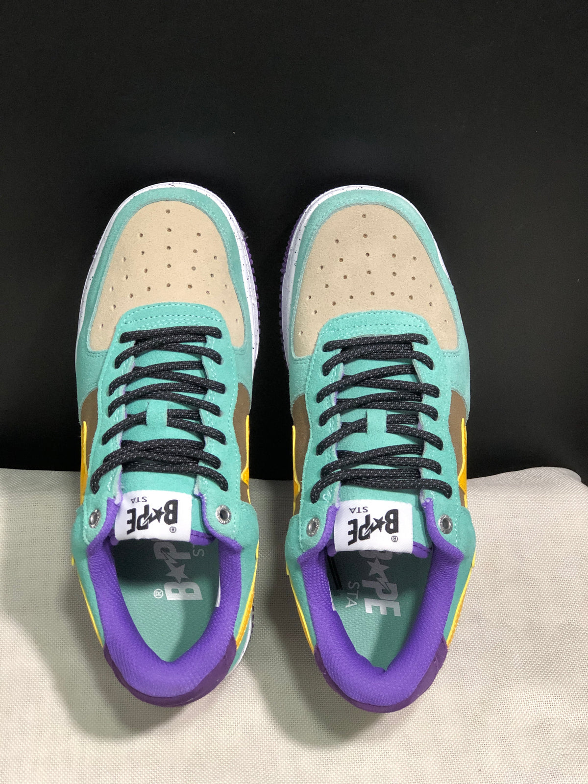 Top view showing perforated beige toe panels, mint green overlays, black laces, and purple padded collars.