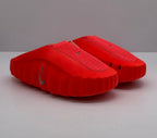 Pair of orange-red Nike slides shown from a front three-quarter angle.