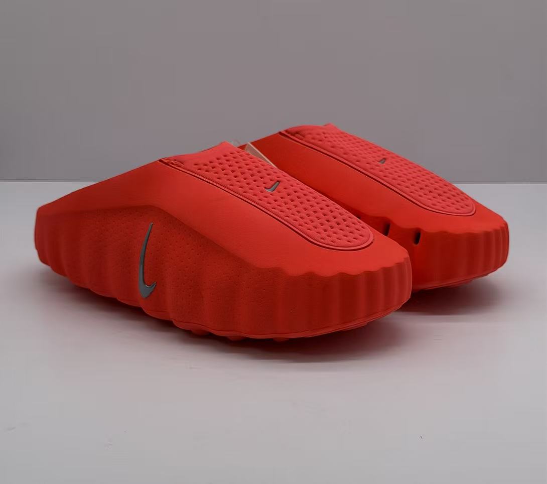 Pair of orange-red Nike slides shown from a front three-quarter angle.