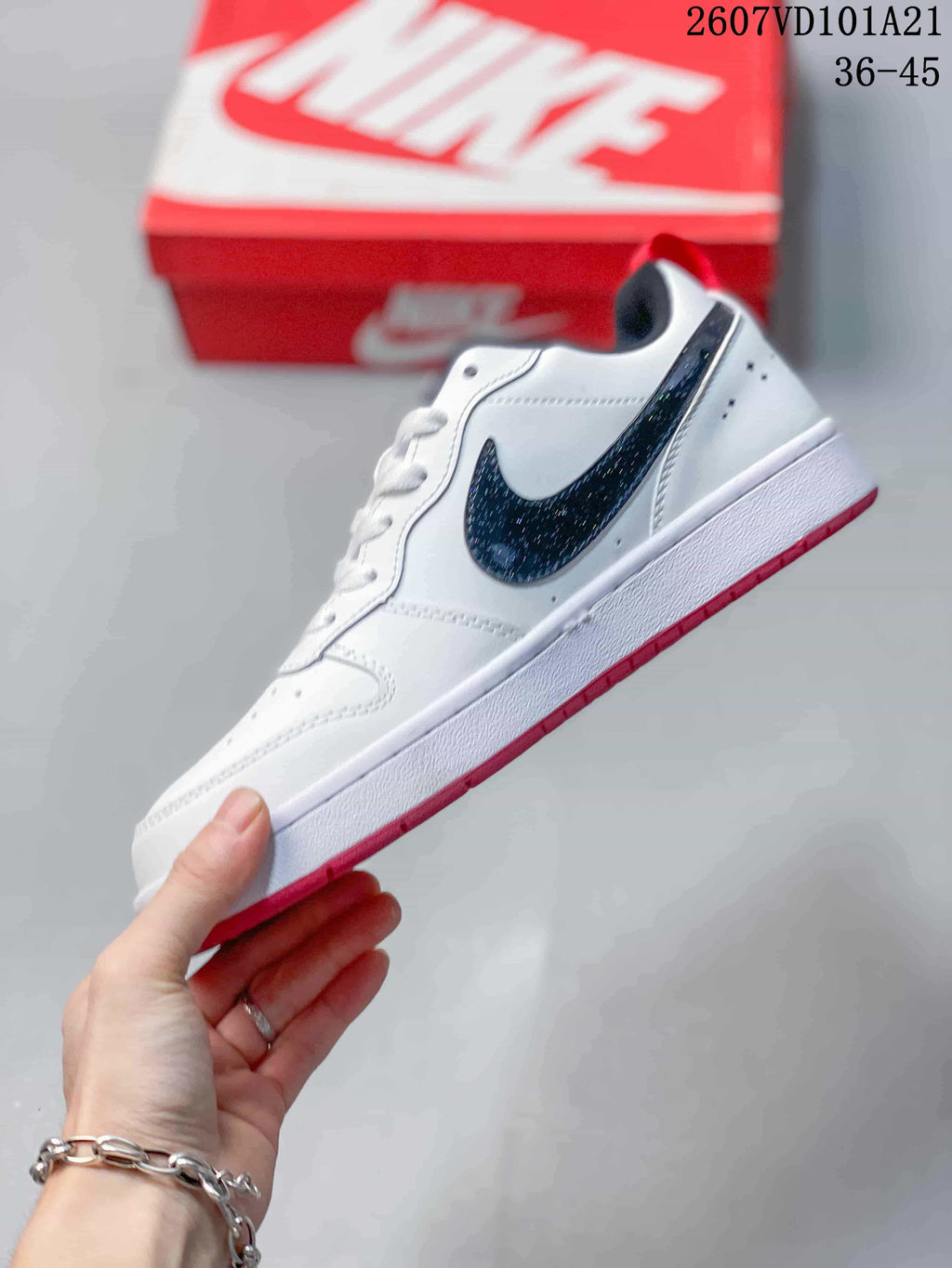Side view of the white Nike sneaker with a contrasting black Swoosh, white midsole and red outsole.