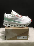 Side view of the white On Cloudmonster 1 sneakers with pale green heel detail, gray side branding, and sculpted white outsole.